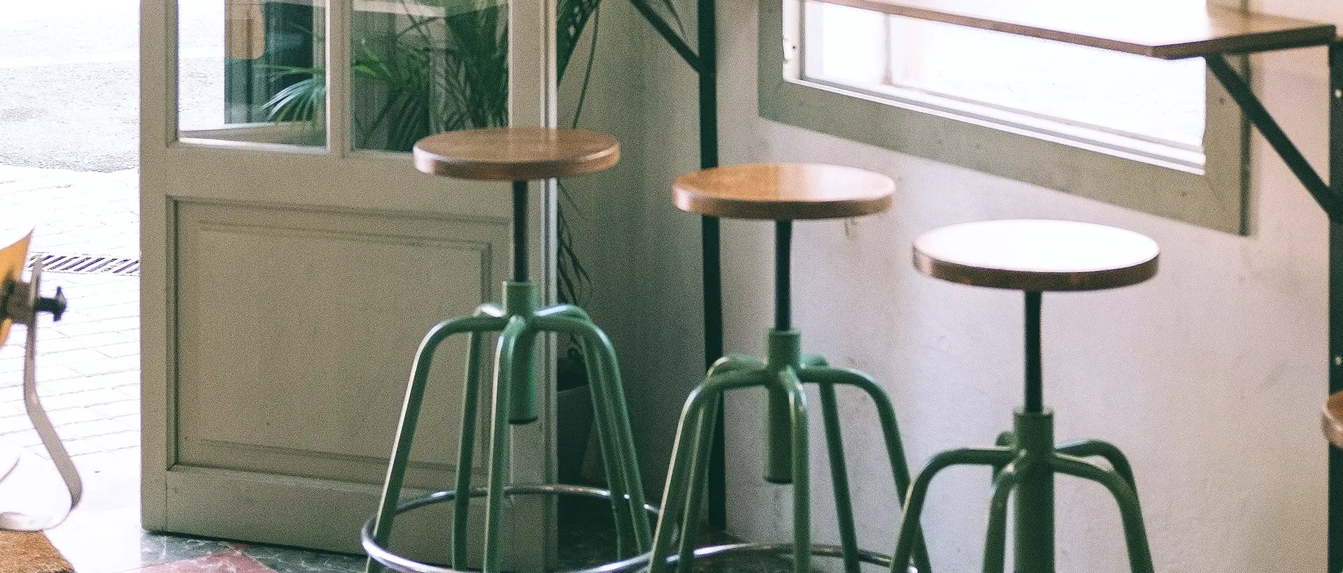 Interior de un bar de barrio con taburetes junto a la ventana